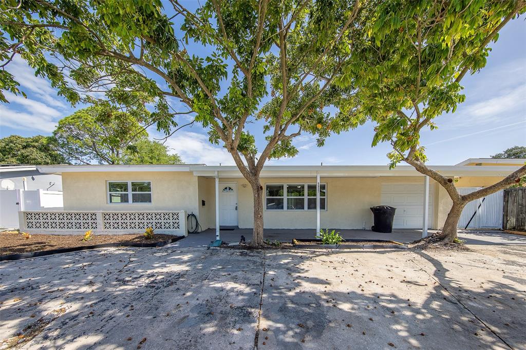 A single-story house with a light-colored exterior, a concrete driveway, and a large shade tree — 5937 38TH AVENUE N, ST PETERSBURG, FL