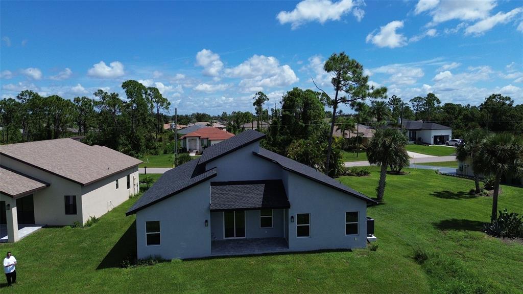 An aerial view shows the rear exterior of a gray house with a dark roof — 275 ANTIS DRIVE, ROTONDA WEST, FL