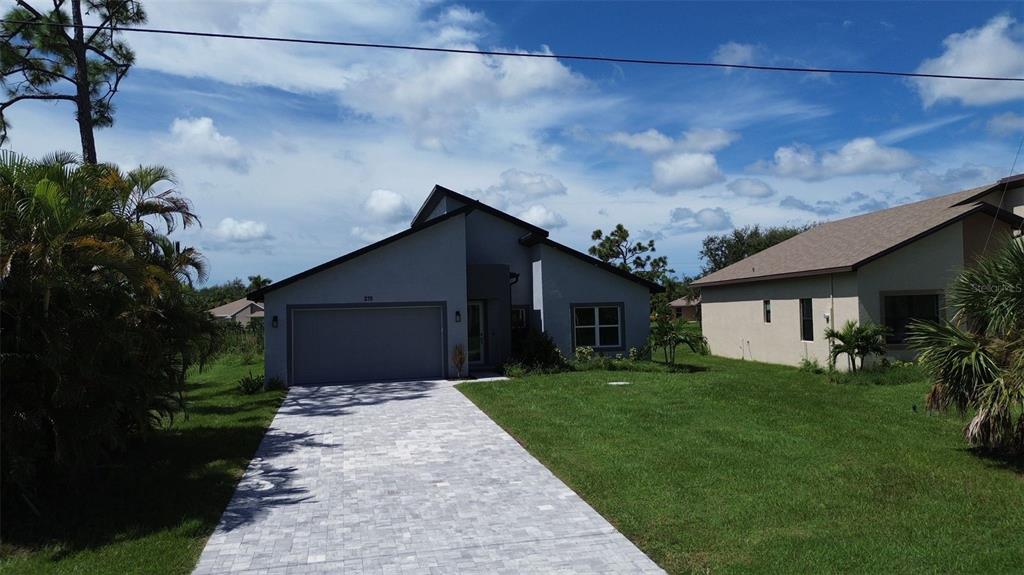 A single-story house with a gray exterior, a paved driveway, and a grassy front yard — 275 ANTIS DRIVE, ROTONDA WEST, FL