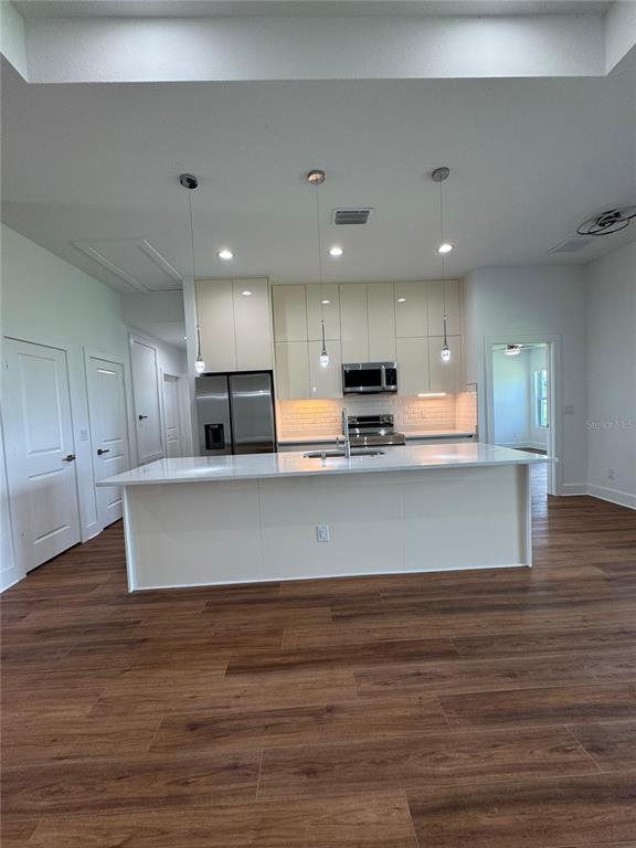 A modern kitchen features a large white island, light-colored cabinetry, and wood-look flooring — 275 ANTIS DRIVE, ROTONDA WEST, FL