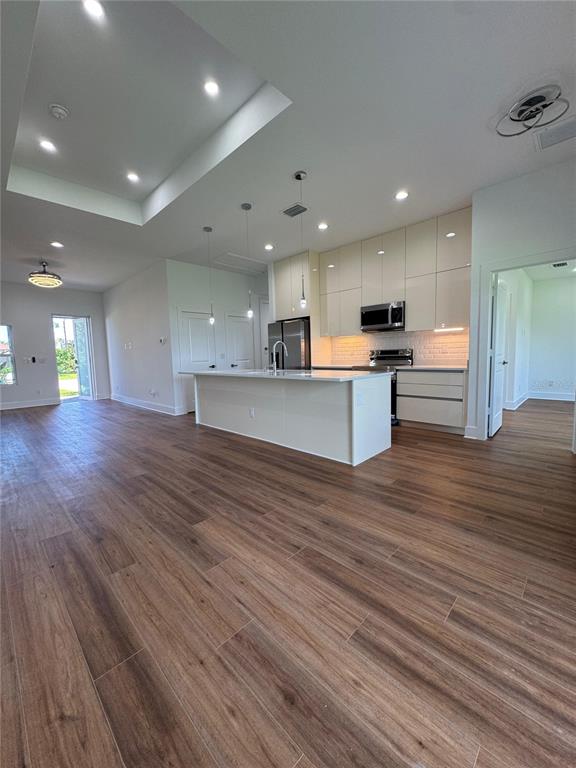 A modern kitchen features a central island, light-colored cabinetry, and wood-look tile flooring — 275 ANTIS DRIVE, ROTONDA WEST, FL