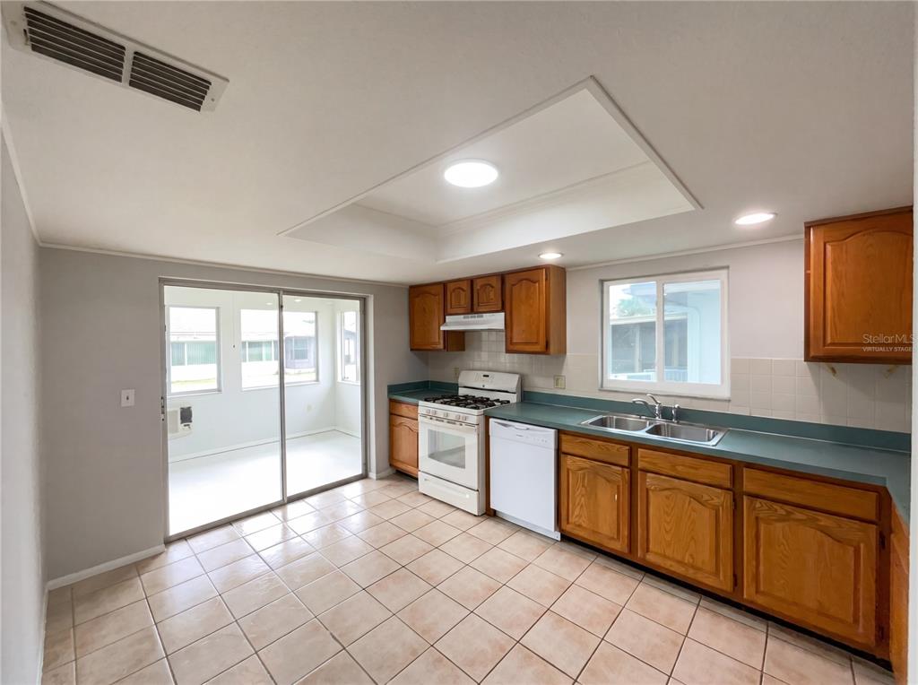 A kitchen with wood cabinets, green countertops, tile flooring, and a sliding glass door — 5508 SILENT BROOK DRIVE, ORLANDO, FL
