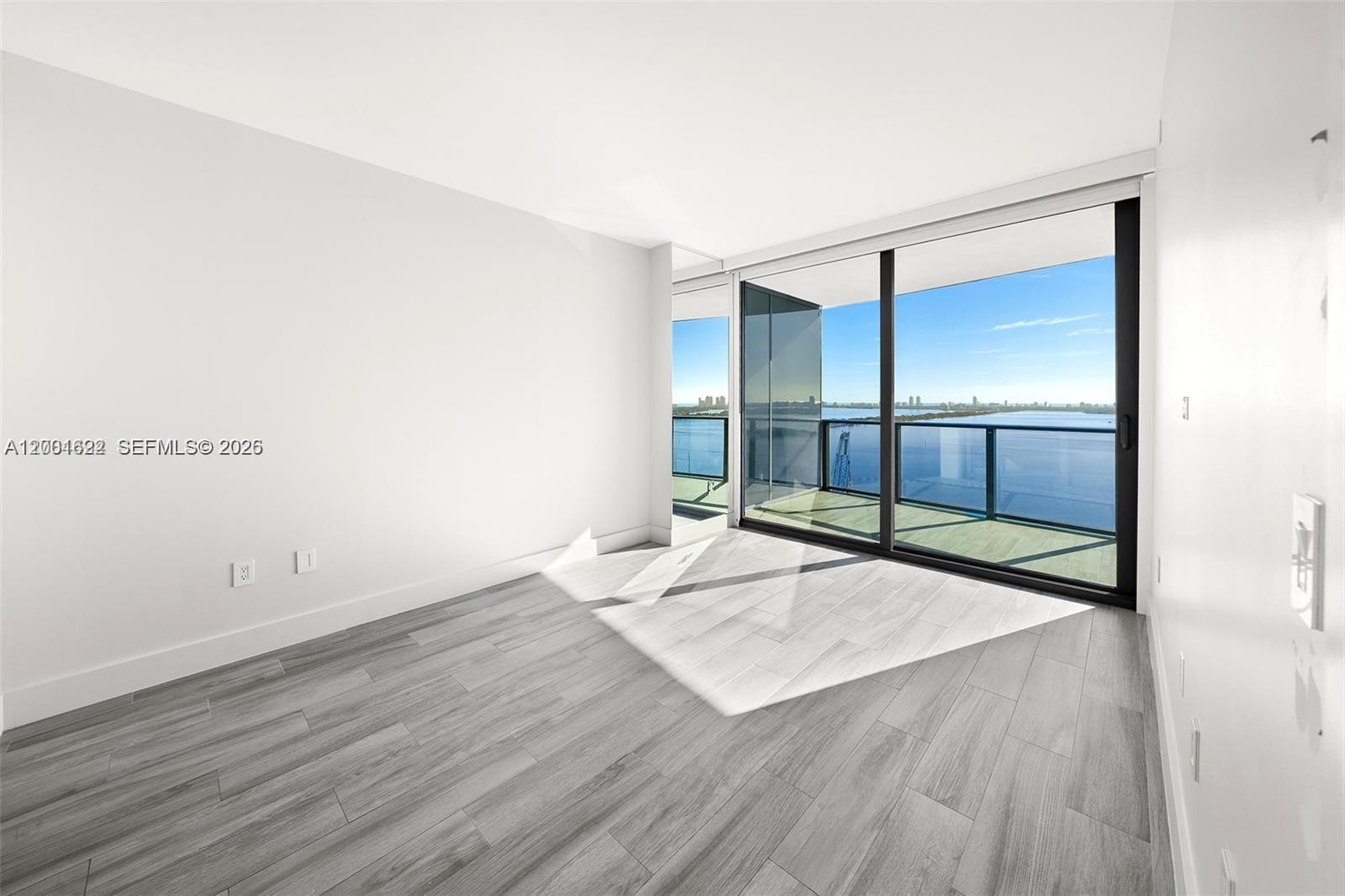 A bright, empty room features light wood-look flooring, white walls, and a large balcony view — 460 NE 28th St # 2707, Miami FL 33137, MIAMI, FL