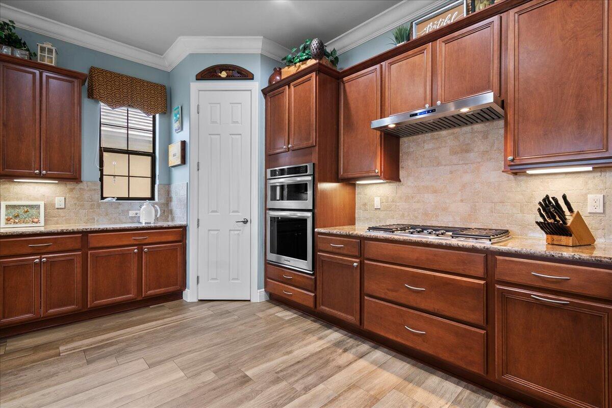 A kitchen features wood cabinets, granite countertops, stainless steel appliances, and light blue walls — 3704 Siena Circle, Wellington FL 33414, WELLINGTON, FL
