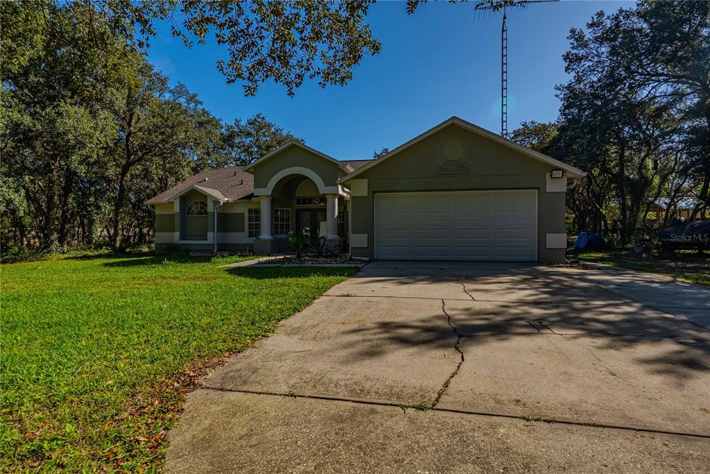 A swimming pool with a screen enclosure sits on a patio next to a house — 14214 CINNAMAN LANE, WEEKI WACHEE, FL