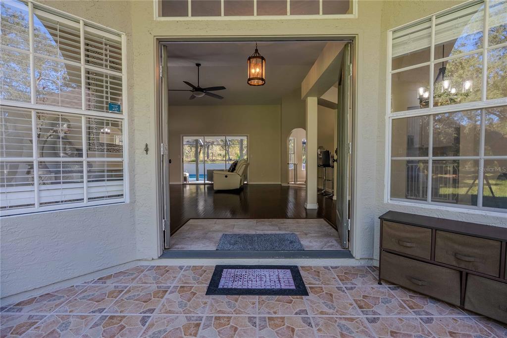A view from a tiled porch through an open doorway into a home's living area — 14214 CINNAMAN LANE, WEEKI WACHEE, FL