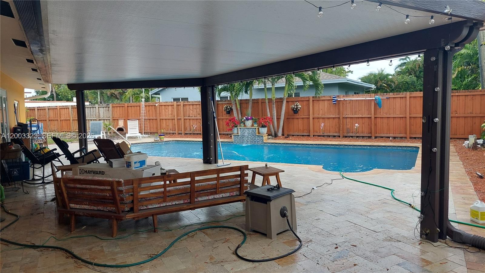 A covered patio features a wooden bench, pool equipment, and a view of a swimming pool — 31 NE 27th Dr, Wilton Manors FL 33334, WILTON MANORS, FL