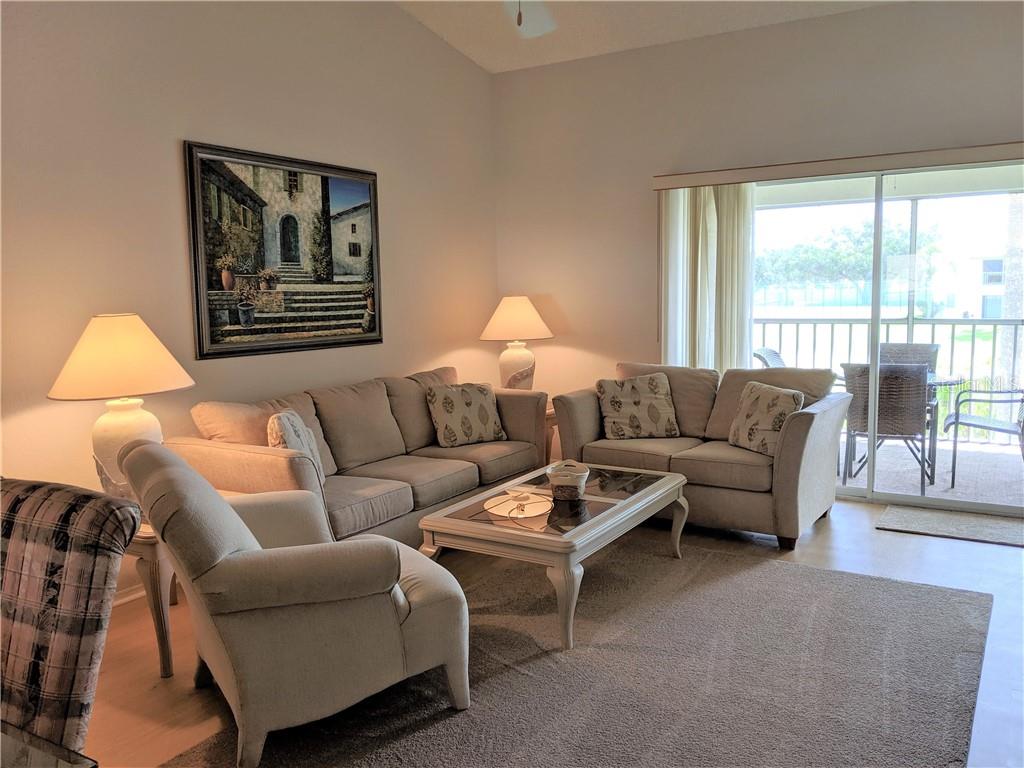 A living room features a beige sofa, loveseat, armchair, coffee table, and a sliding glass door — 4378 MADERIA COURT COURT UNIT n/a, SARASOTA, FL