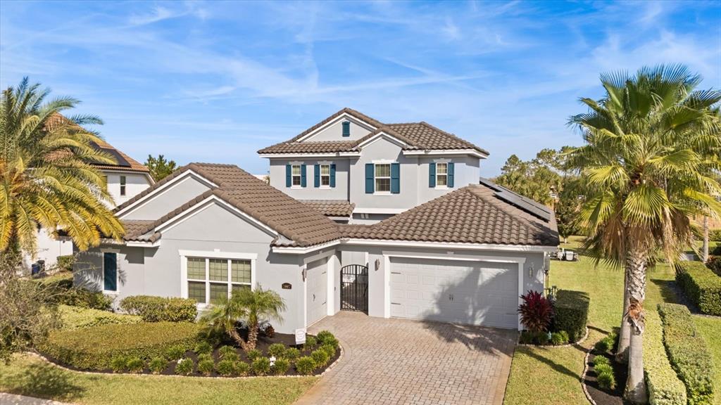 A two-story gray house with a tiled roof, a paved driveway, and palm trees — 7667 BLUE QUAIL LANE, ORLANDO, FL