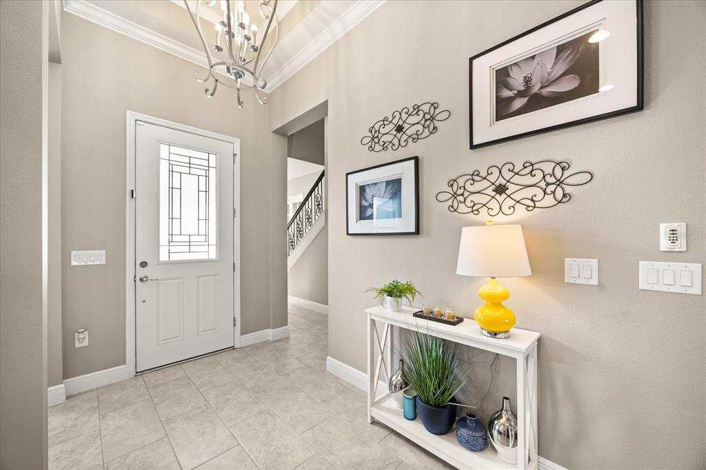 A bright entryway features a white front door, tile flooring, and a console table — 7667 BLUE QUAIL LANE, ORLANDO, FL