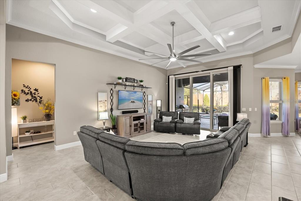 A living room features a coffered ceiling, a large sectional sofa, and a television console — 7667 BLUE QUAIL LANE, ORLANDO, FL