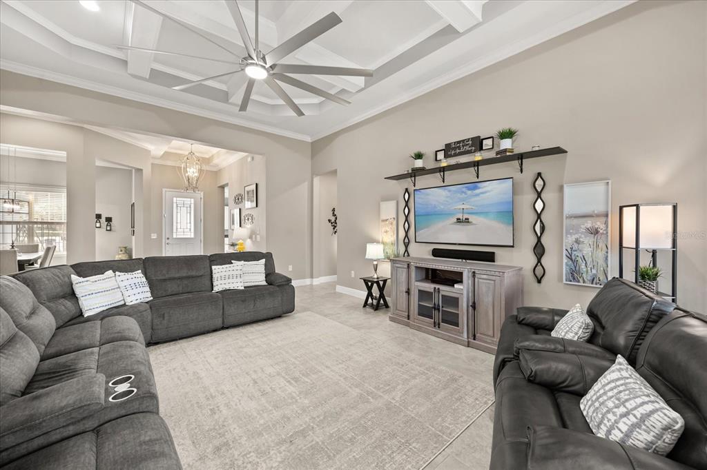 A spacious living room features a large sectional sofa, a television console, and a ceiling fan — 7667 BLUE QUAIL LANE, ORLANDO, FL
