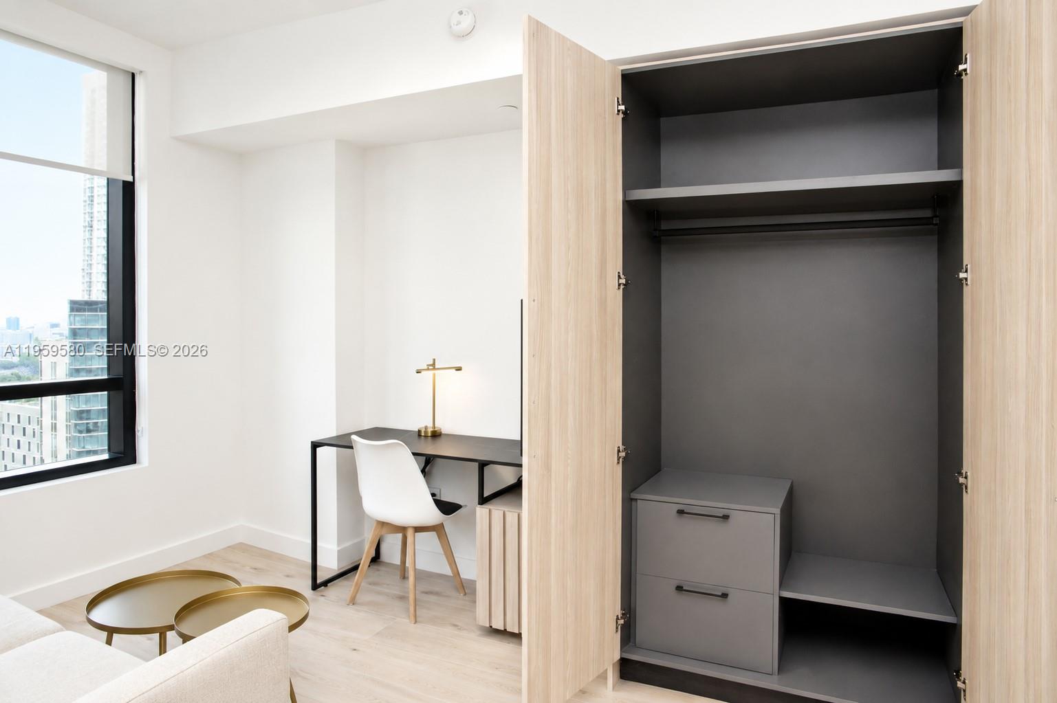 A modern room features a desk, a white chair, and an open light-wood wardrobe — 225 N Miami Ave # 2306, Miami FL 33128, MIAMI, FL