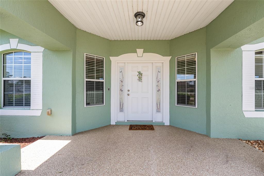 The exterior view shows a covered front porch with a white door and windows — 5330 PECAN RD, OCALA, FL