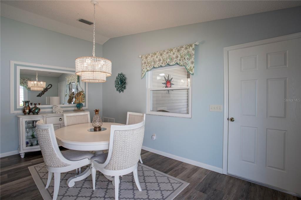 A dining room features a round table, four chairs, a chandelier, and light blue walls — 17403 SE 77TH SYCAMORE AVENUE, THE VILLAGES, FL