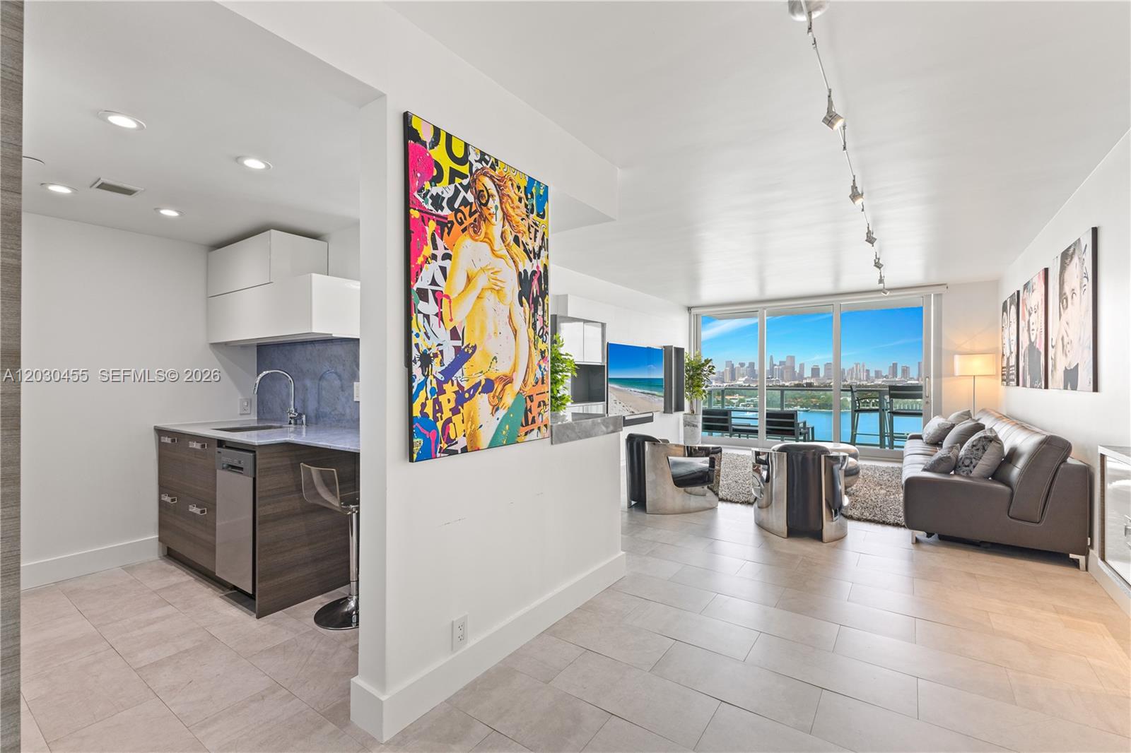 A modern apartment features an open kitchen, a living area with city views, and artwork — 1000 West Ave # 1518, Miami Beach FL 33139, MIAMI BEACH, FL