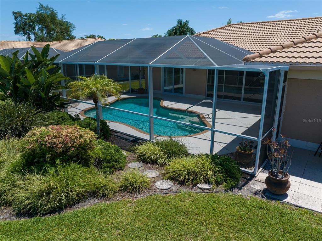 A screened-in swimming pool sits on a patio behind a house with a tiled roof — 3162 E VILLAGE DRIVE, VENICE, FL