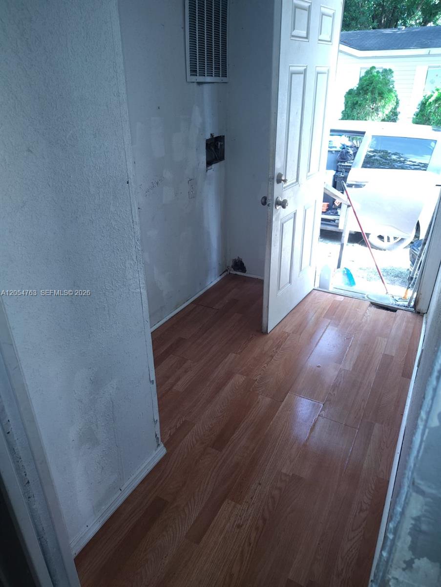A laundry area with wood-look flooring and an open door leading to an outdoor space — 26 Candlelight Dr, Lake Wales FL 33859, LAKE WALES, FL