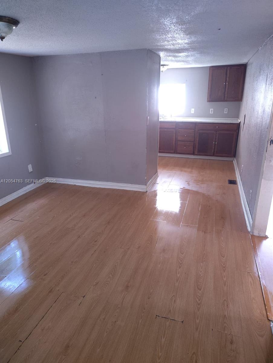 A room with light wood-look flooring leads into a kitchen with dark wood cabinets — 26 Candlelight Dr, Lake Wales FL 33859, LAKE WALES, FL