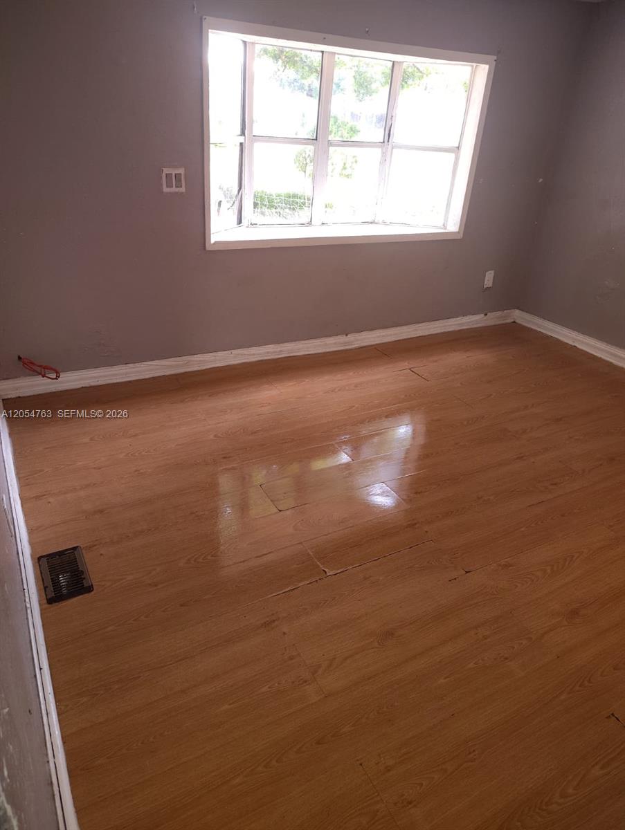 An empty room features light-colored wood-look flooring, gray walls, and a large window — 26 Candlelight Dr, Lake Wales FL 33859, LAKE WALES, FL