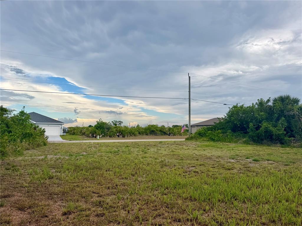 A vacant, grassy residential lot sits in front of a paved road and neighboring houses — 171 WRIGHT DRIVE, ROTONDA WEST, FL