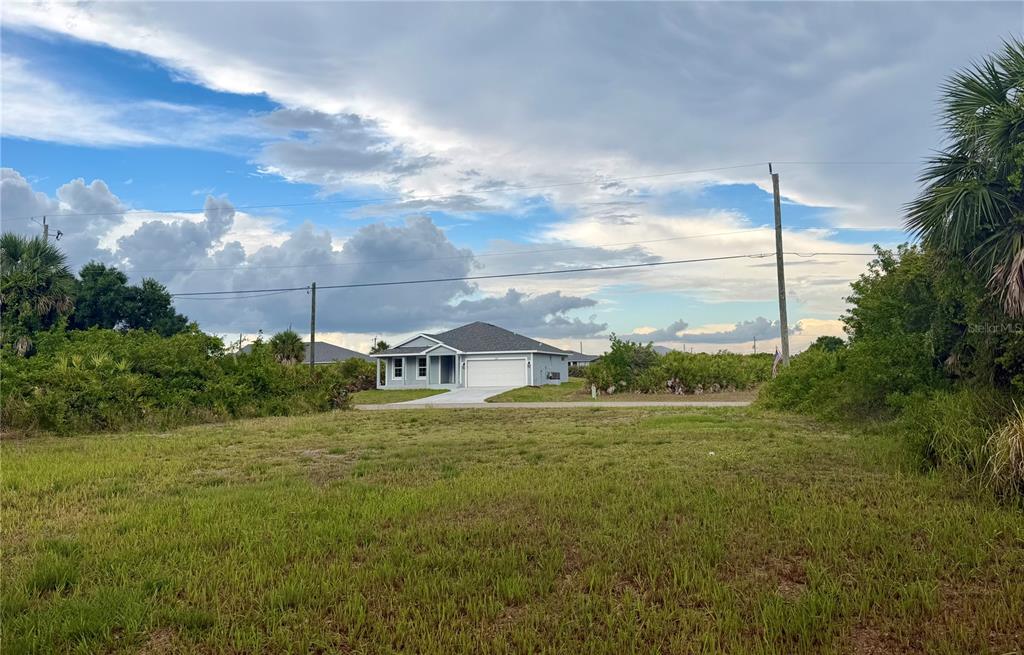 A single-story house with a garage sits behind a large, grassy vacant lot — 171 WRIGHT DRIVE, ROTONDA WEST, FL