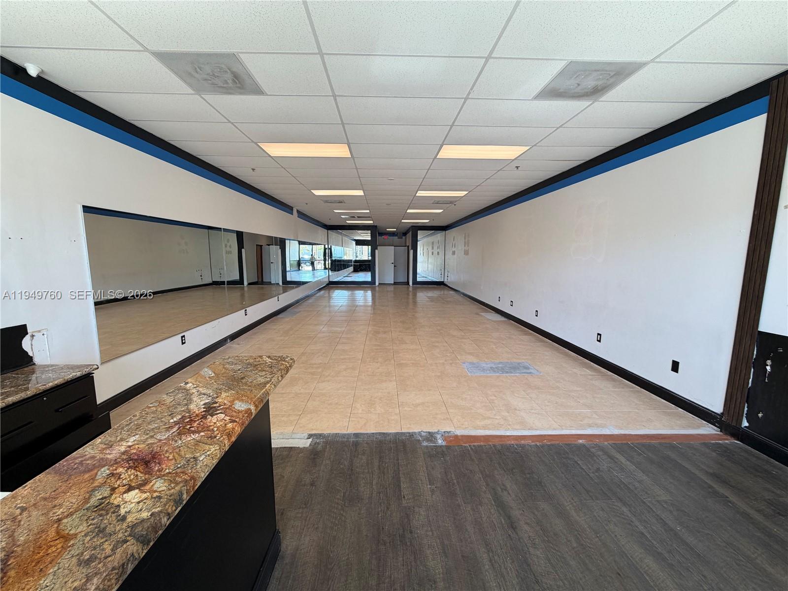 An empty commercial space features tile flooring, mirrored walls, and a granite-topped reception counter — 4570 Lyons Rd # 105, Coconut Creek FL 33073, COCONUT CREEK, FL