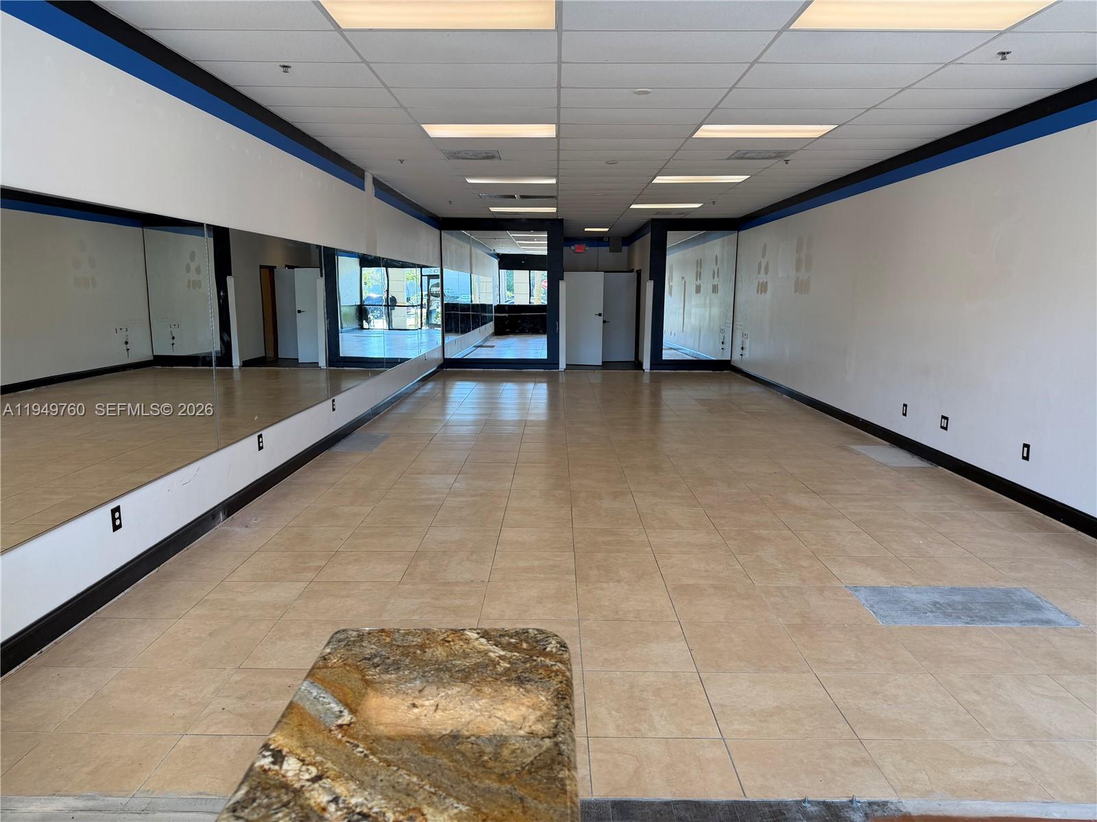 An empty commercial space features tiled floors, mirrored walls, and a granite-topped counter — 4570 Lyons Rd # 105, Coconut Creek FL 33073, COCONUT CREEK, FL
