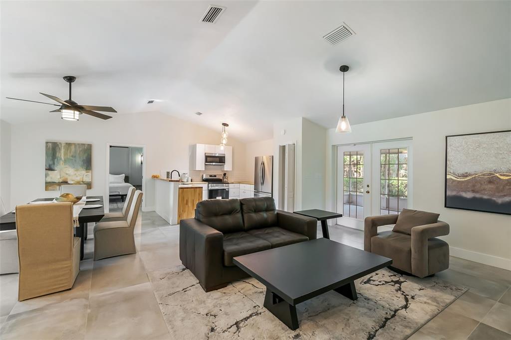An open-concept living and dining area features tile floors, a dark sofa, and white cabinetry — 3222 SW 27TH STREET, GAINESVILLE, FL