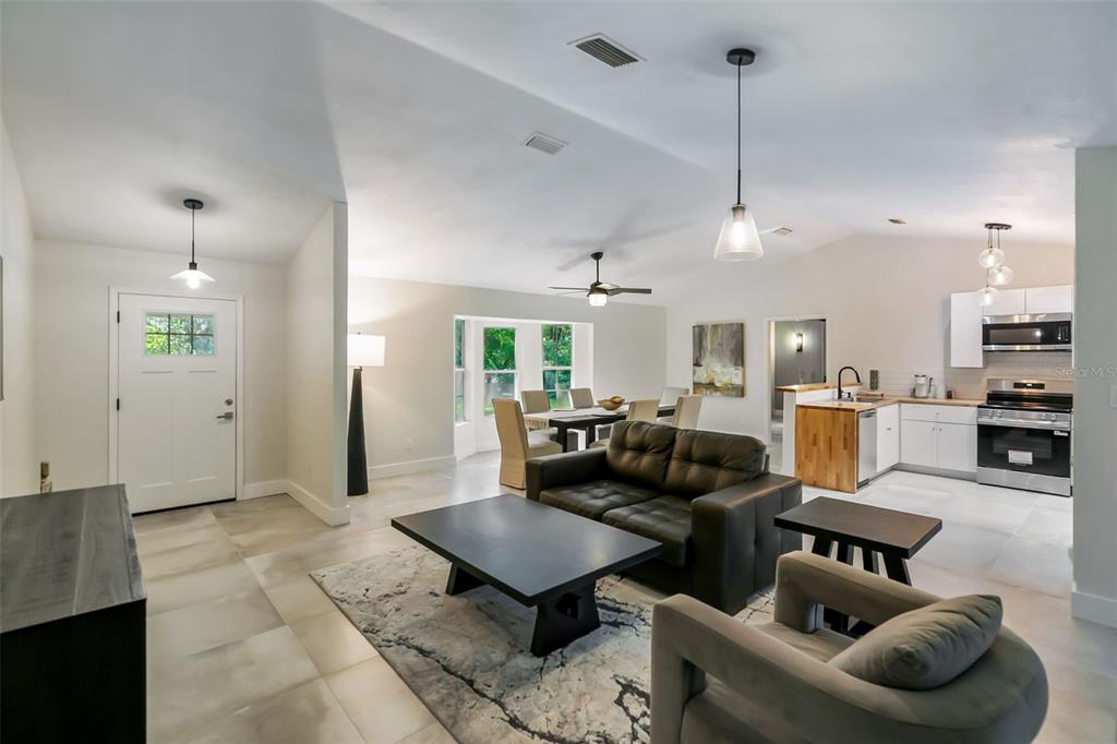 An open-concept living room and kitchen feature tile flooring, a dark sofa, and dining area — 3222 SW 27TH STREET, GAINESVILLE, FL