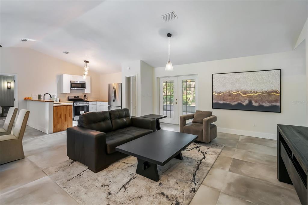 A living room with tile floors, a black sofa, a coffee table, and an open kitchen — 3222 SW 27TH STREET, GAINESVILLE, FL