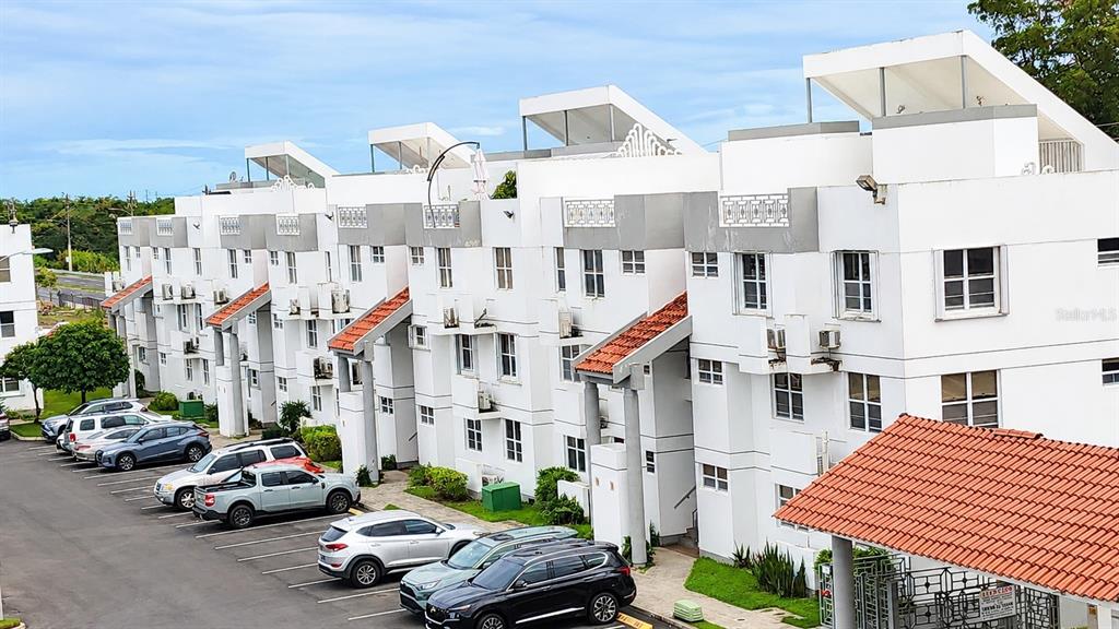 An exterior view of a multi-story white apartment complex with a parking lot — 500 PASEO DEL RIO UNIT 4803, HUMACAO, PR