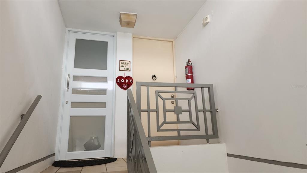 A white door with glass panels and a metal railing lead to an interior staircase — 500 PASEO DEL RIO UNIT 4803, HUMACAO, PR