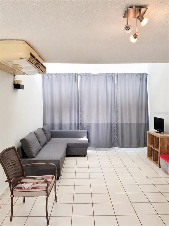 A living room features a grey sectional sofa, a wicker chair, and white tile flooring — 500 PASEO DEL RIO UNIT 4803, HUMACAO, PR