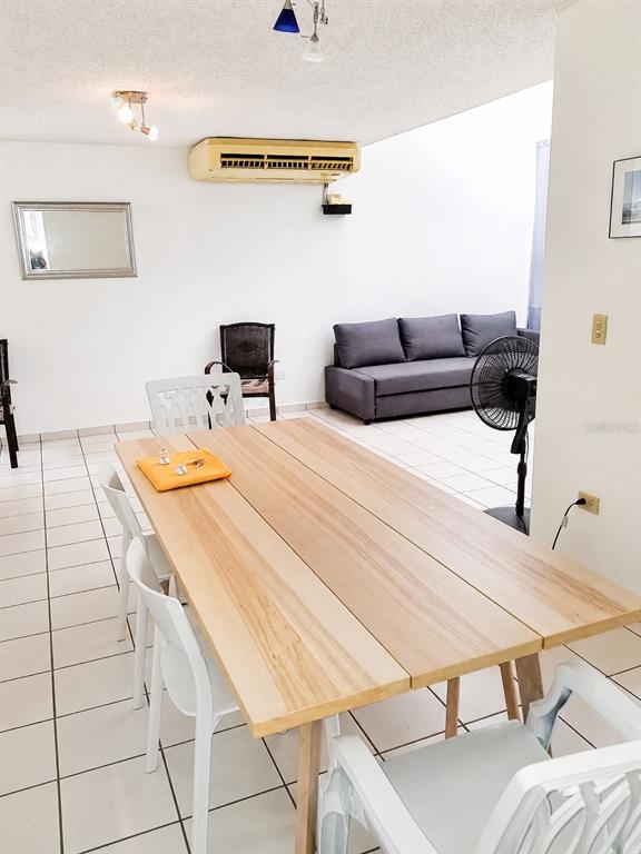 A dining area with a wooden table and white chairs opens into a living room — 500 PASEO DEL RIO UNIT 4803, HUMACAO, PR
