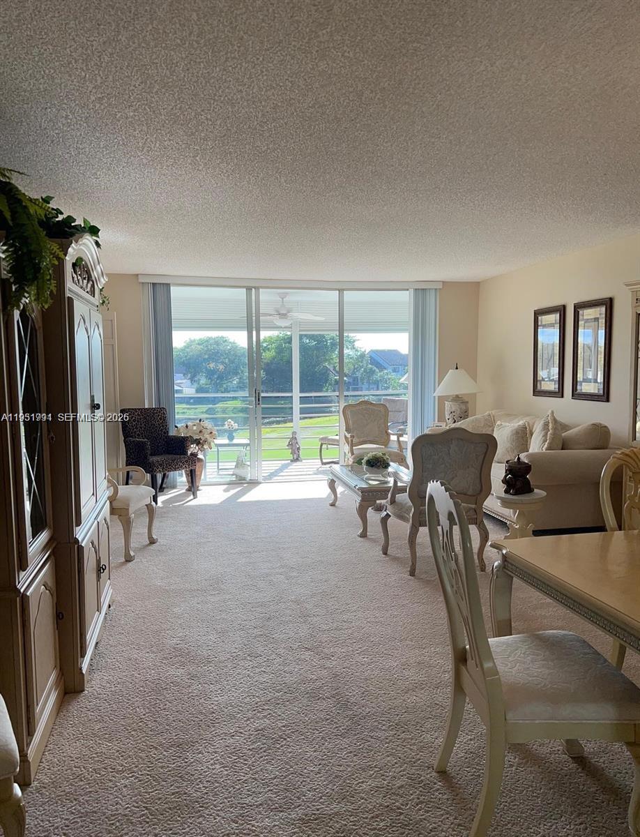 A living room features carpeted floors, traditional furniture, and a sliding glass door overlooking water — 821 Cypress Blvd # 312, Pompano Beach FL 33069, POMPANO BEACH, FL