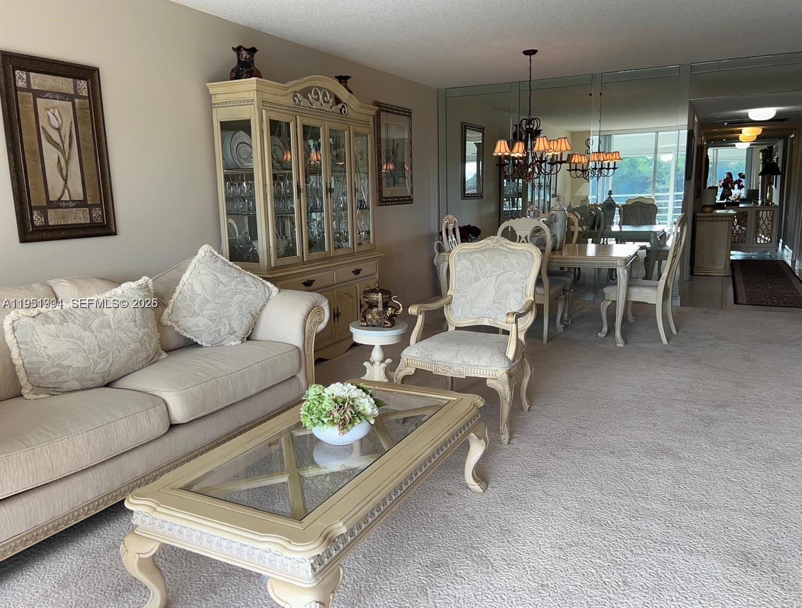 A living and dining room area features beige furniture, a glass coffee table, and mirrored walls — 821 Cypress Blvd # 312, Pompano Beach FL 33069, POMPANO BEACH, FL