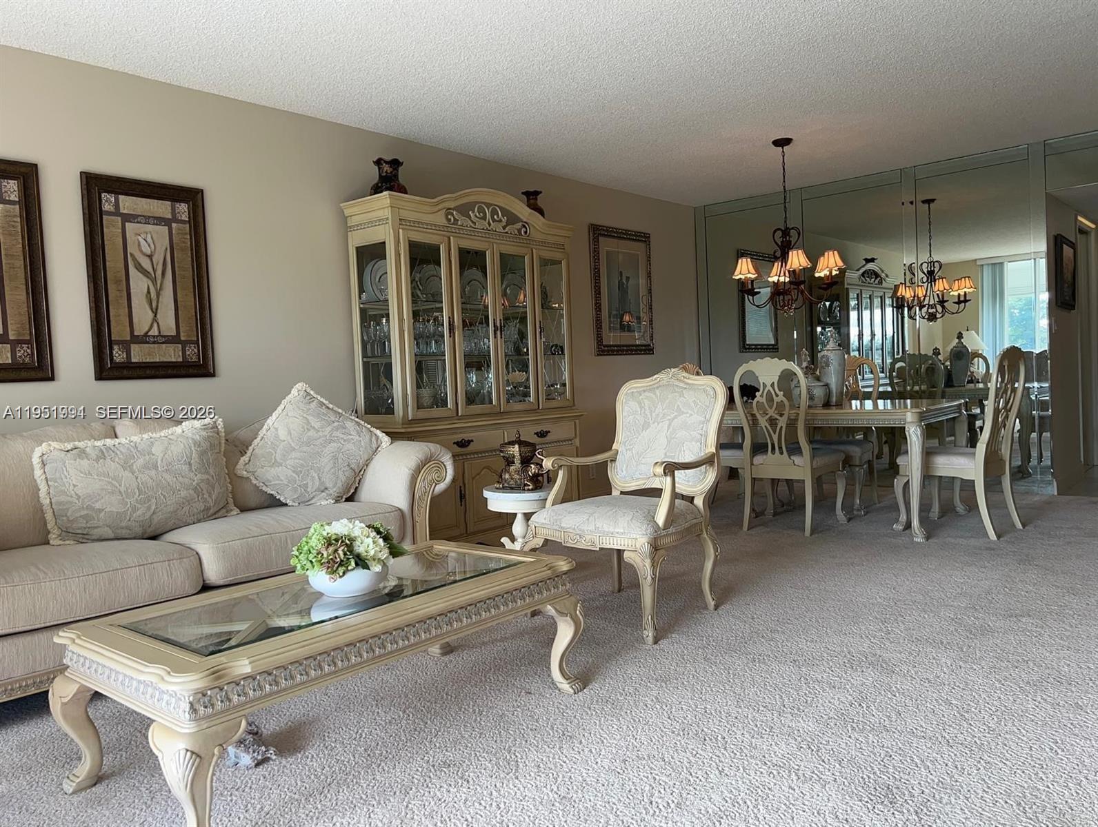 A living and dining area features traditional furniture, a glass-topped coffee table, and mirrored walls — 821 Cypress Blvd # 312, Pompano Beach FL 33069, POMPANO BEACH, FL