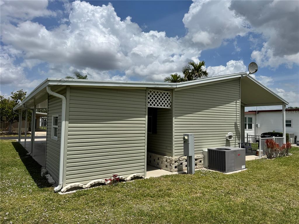 The exterior of a light green mobile home features a side entrance and an air conditioner — 346 ANDROS DRIVE, SARASOTA, FL