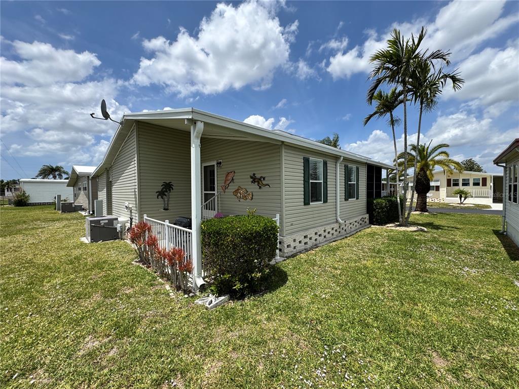 A light-colored manufactured home features a small front porch, vinyl siding, and palm trees — 346 ANDROS DRIVE, SARASOTA, FL