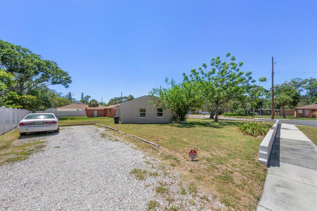 A gravel driveway leads to a single-story house with a lawn and mature trees — 1135 FAIRMONT STREET, CLEARWATER, FL