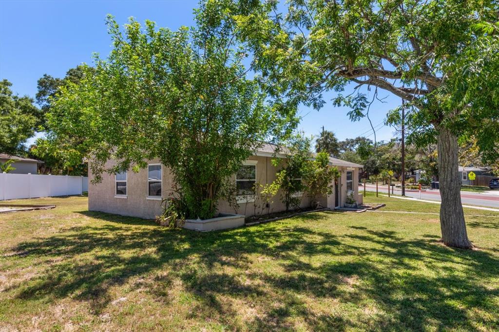 A single-story house with a tan stucco exterior sits on a grassy lot with trees — 1135 FAIRMONT STREET, CLEARWATER, FL