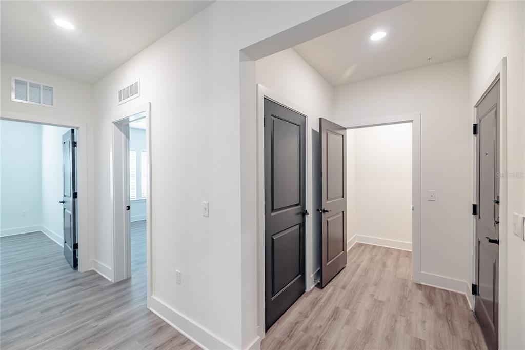 A hallway with gray wood-look flooring, white walls, and several dark gray interior doors — 1420 LAKEFRONT DRIVE UNIT 7111, SARASOTA, FL
