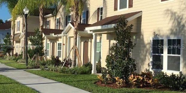 A row of beige multi-story townhouses with palm trees and a sidewalk in front — 3207 OYSTER LANE, KISSIMMEE, FL