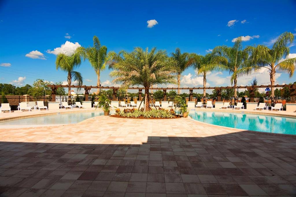 A swimming pool with lounge chairs and palm trees under a bright blue sky — 3207 OYSTER LANE, KISSIMMEE, FL