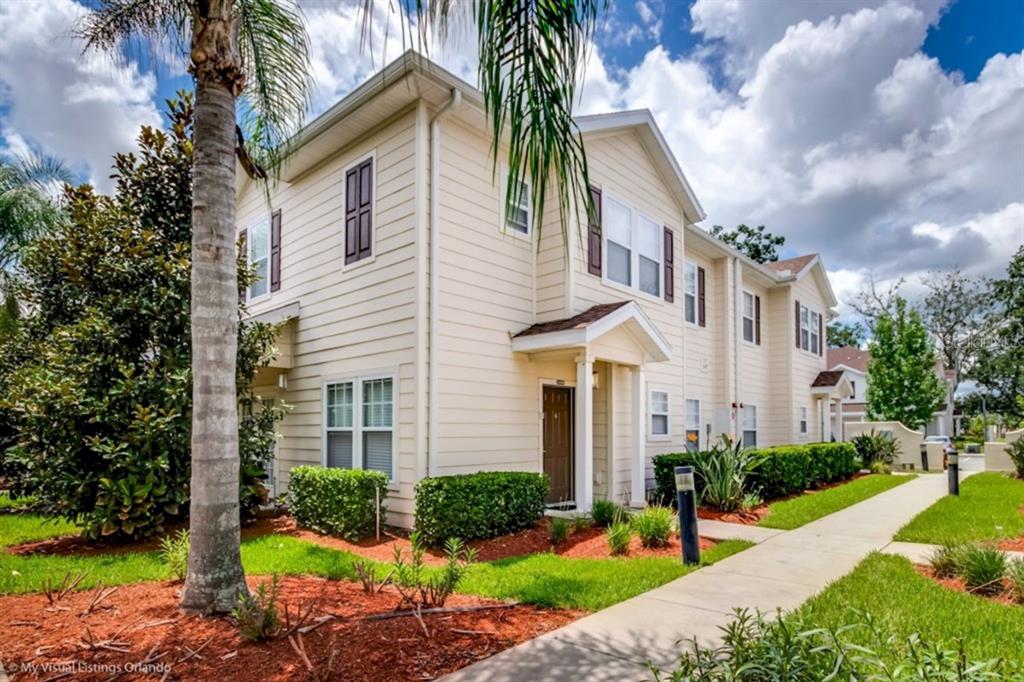 A two-story beige townhouse with a brown front door and a sidewalk in front — 3207 OYSTER LANE, KISSIMMEE, FL