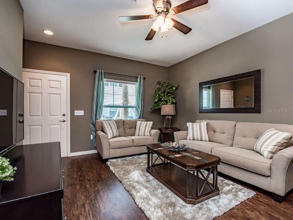 A living room features a beige sofa and loveseat, dark wood furniture, and a ceiling fan — 3207 OYSTER LANE, KISSIMMEE, FL