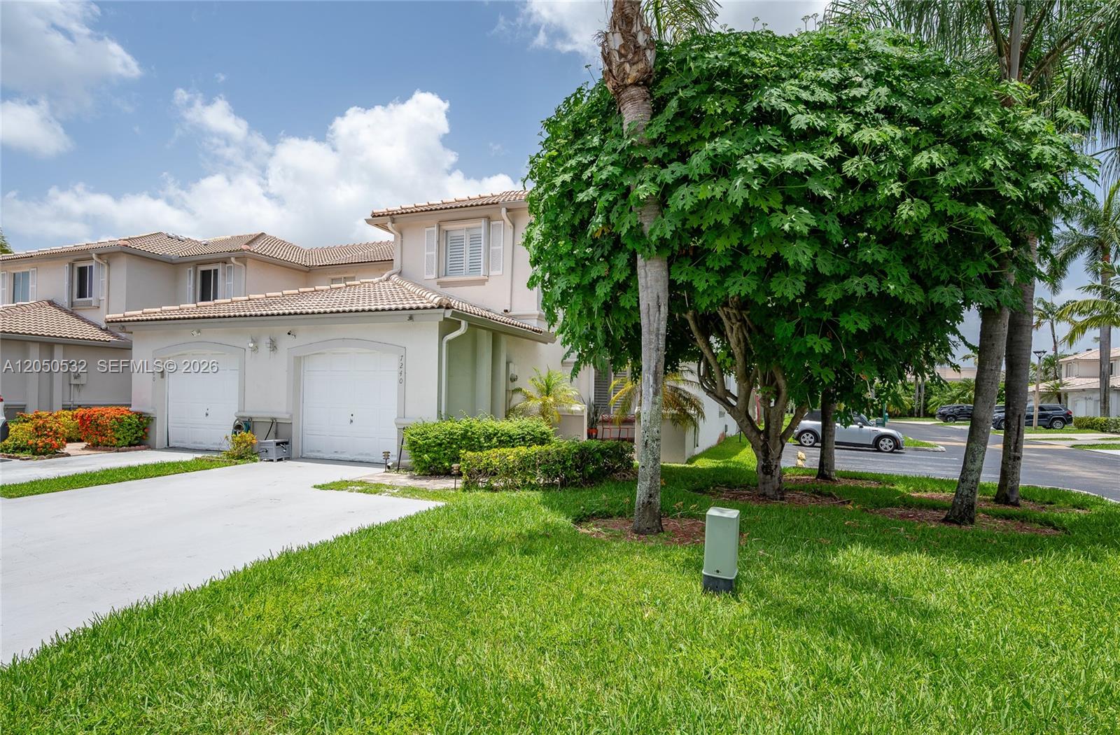 A two-story townhouse with a two-car garage, light-colored stucco exterior, and a large tree — 7240 SW 162nd Ct, Miami FL 33193, MIAMI, FL