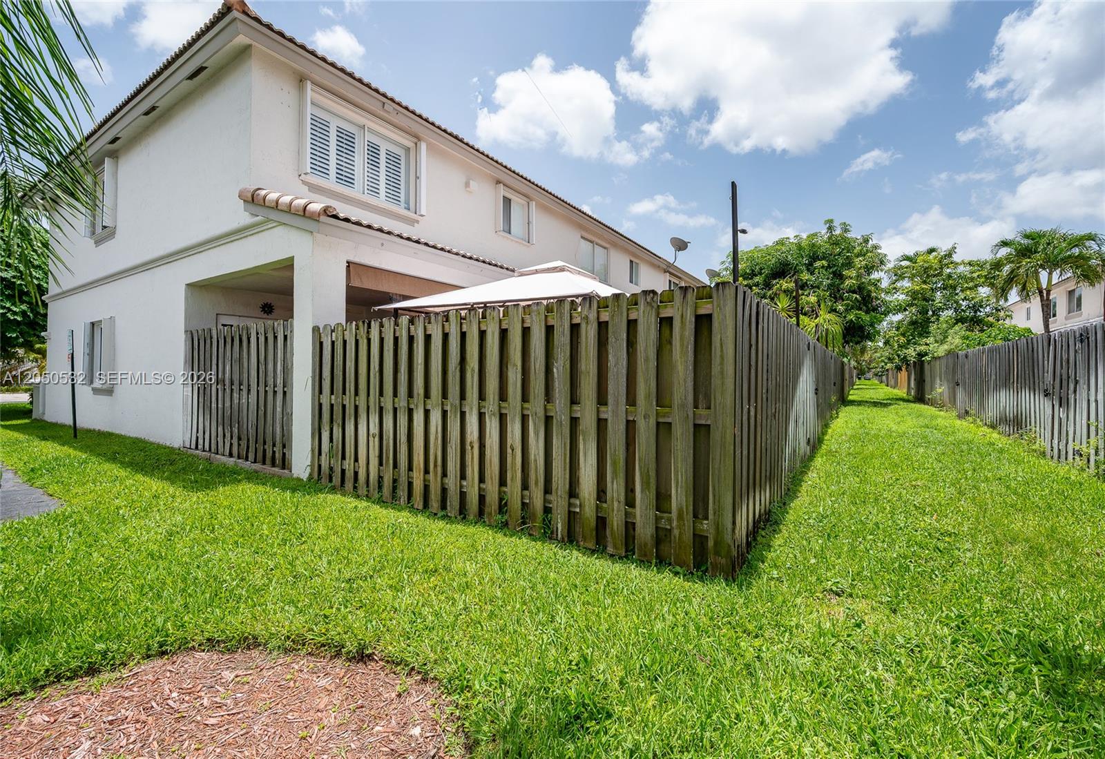 A two-story white stucco townhouse features a wooden privacy fence enclosing a backyard patio area — 7240 SW 162nd Ct, Miami FL 33193, MIAMI, FL