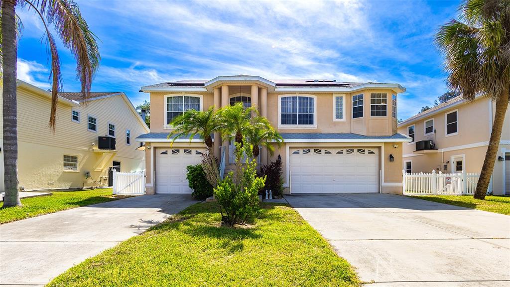 A two-story suburban house with a three-car garage and palm trees in the front yard — 5451 TROPIC DRIVE, NEW PORT RICHEY, FL